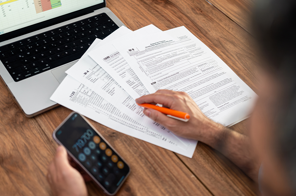 Persona optimizando sus finanzas con una calculadora y documentos, que simboliza el ahorro por deducciones fiscales.