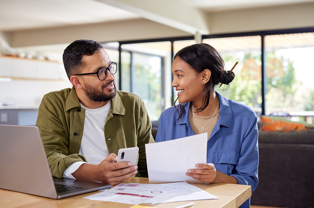 Pareja joven revisando juntos su plan financiero en una mesa, simbolizando la planeación y el ahorro familiar.